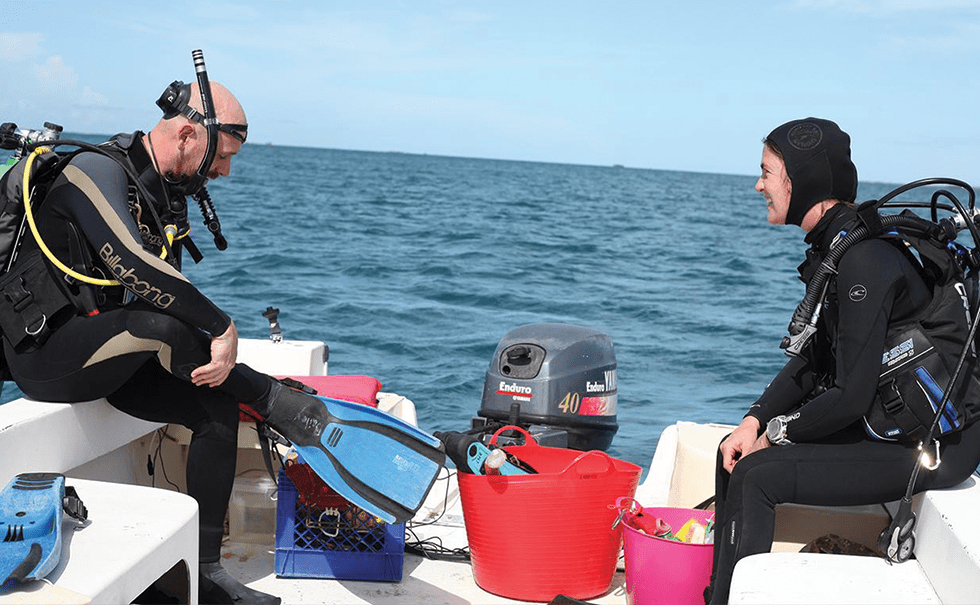 Image of two researchers wearing wetsuits and sitting on a research boat